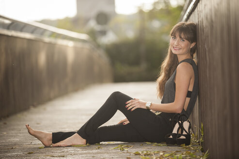Lächelnde junge Frau entspannt sich auf einer Fußgängerbrücke - PAF001085