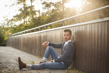 Stylish young man sitting on a footbridge - PAF001079