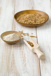 Bowl of emmer, Triticum dicoccum, and bowl of whole meal on light wood - MYF000692