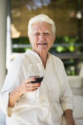 Porträt einer lächelnden älteren Frau mit einem Glas Rotwein - ABAF001575