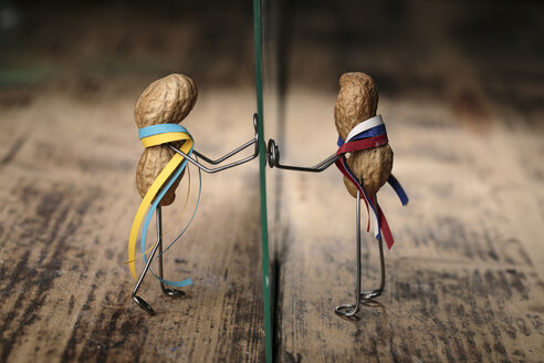 Peanut manikins with Ukrainian and Russian national colours separated through glass pane - NIF000020