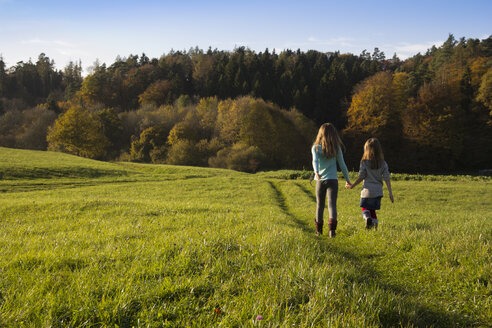 Deutschland, Bayern, Landshut, zwei Mädchen spazieren auf einer Wiese im Herbst - YFF000260