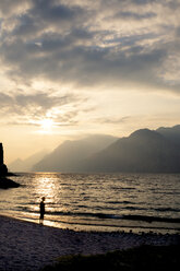 Italien, Venetien, Malcesine, Junge steht am Gardasee im Abendlicht - LVF002169