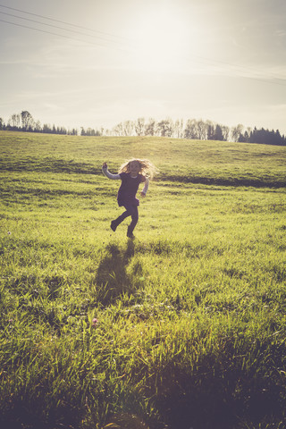 Little girl jumping on a meadow in backlight stock photo