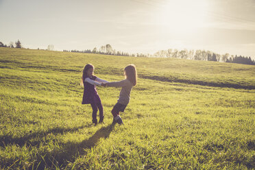 Two little girls turning around together on a meadow in backlight - SARF001006