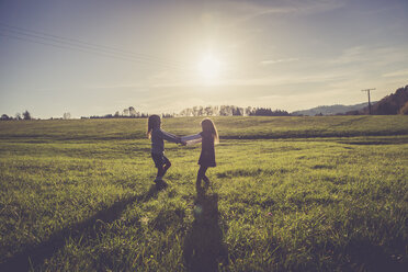 Two little girls turning around together on a meadow in backlight - SARF001007