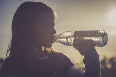 Mädchen trinkt Wasser aus einer Wasserflasche bei Gegenlicht - SARF001021
