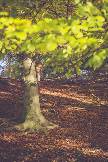 Kleines Mädchen versteckt sich hinter einem Baum im Wald - SARF001011