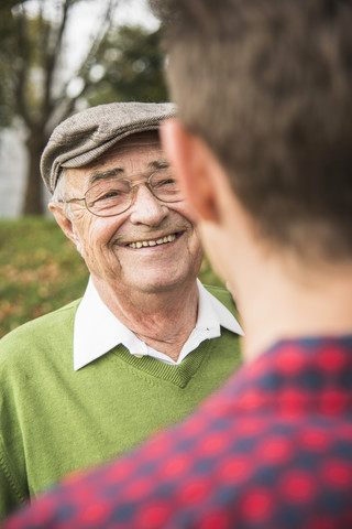Älterer Mann lächelt erwachsenen Enkel an, lizenzfreies Stockfoto