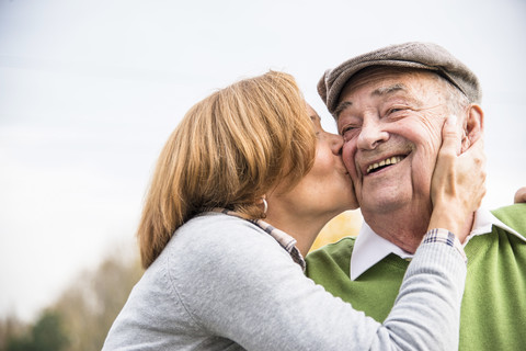 Erwachsene Tochter küsst Vater auf die Wange, lizenzfreies Stockfoto