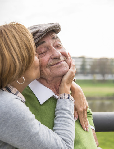 Adult daughter kissing father's cheek stock photo