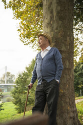 Senior man standing at tree trunk - UUF002723