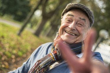 Portrait of happy senior man outdoors doing victory sign - UUF002712