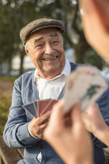 Senior man and grandson playing cards - UUF002713