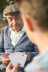 Älterer Mann und Enkel spielen Karten - UUF002715