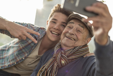 Glücklicher älterer Mann macht ein Selfie mit seinem Enkel, lizenzfreies Stockfoto