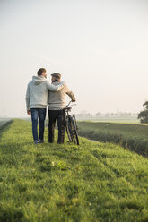 Älterer Mann und Enkel in ländlicher Landschaft mit Fahrrad - UUF002700