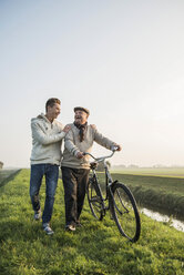 Älterer Mann und Enkel in ländlicher Landschaft mit Fahrrad - UUF002701