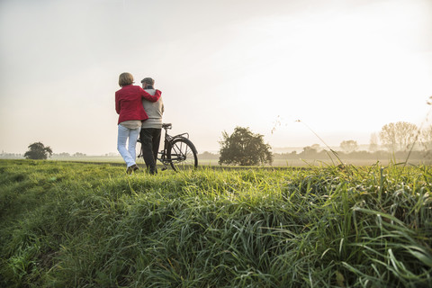 Älterer Mann und Tochter in ländlicher Landschaft mit Fahrrad, lizenzfreies Stockfoto