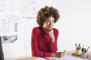 Portrait of smiling young female architect sitting at her desk - EBSF000334