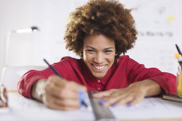 Portrait of laughing young female architect working at her desk - EBSF000336