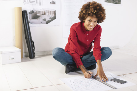 Junge Architektin bei der Arbeit auf dem Boden ihres Büros, lizenzfreies Stockfoto