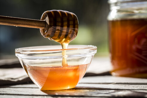 Honig, der von einem Honiglöffel in eine Glasschale tropft - SARF001031