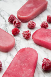 Raspberry ice lollies and frozen raspberries on marble - LVF002208