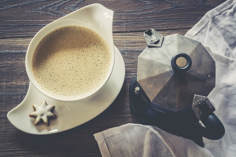 Tasse Kaffee, Zimtstern und Espressodose auf dunklem Holz, lizenzfreies Stockfoto