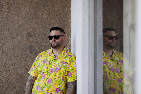 Mann mit Vollbart und Tattoos trägt Hemd mit Blumenmuster und Sonnenbrille - HCF000079