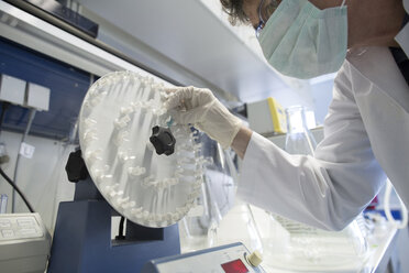 Technikerin, die eine Probe in einen Rotator im Biochemielabor einlegt - SGF001058