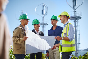 Business partners looking at wind turbine schematics with engineer - ZEF002248