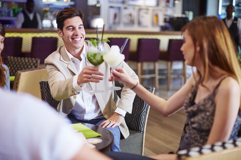 Mann und Frau stoßen an der Hotelbar mit Cocktailgläsern an - ZEF002488