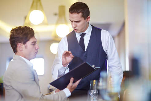 Geschäftsmann gibt eine Bestellung bei einem Kellner im Hotelrestaurant auf - ZEF002491