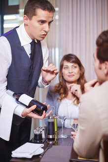 Kellner zeigt Geschäftspartnern im Hotelrestaurant eine Weinflasche - ZEF002732