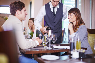 Waiter pouring wine for business associates at hotel restaurant - ZEF002492