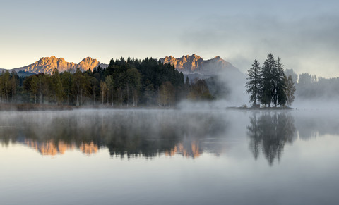 Österreich, Tirol, Kitzbühel, Blick auf den Schwarzsee mit Morgennebel und Kitzbüheler Alpen im Hintergrund, lizenzfreies Stockfoto