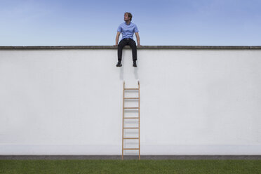 Business man sitting on wall, ladder - RBF002228