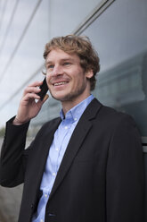 Portrait of smiling businessman telephoning with smartphone - RBF002069