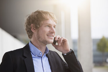 Portrait of smiling businessman telephoning with smartphone - RBF002070