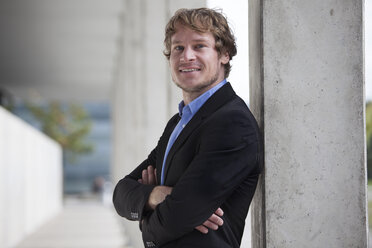 Portrait of smiling businessman with crossed arms - RBF002074