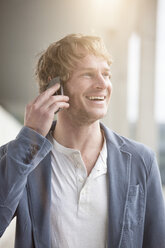 Porträt eines lächelnden Mannes, der mit einem Smartphone telefoniert - RBF002076