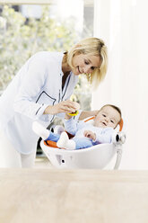 Mother playing with baby boy in seat - GDF000579