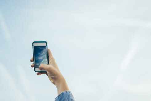 Germany, woman shooting to sky with a smartphone - JPF000022