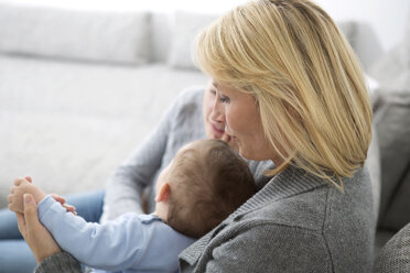 Mutter sitzt mit Tochter und kleinem Jungen auf der Couch - GDF000590