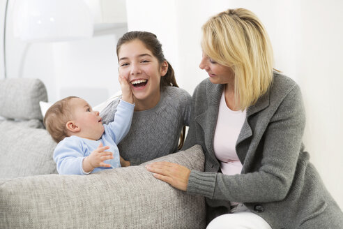 Mutter sitzt mit Tochter und kleinem Jungen auf der Couch und lächelt - GDF000591
