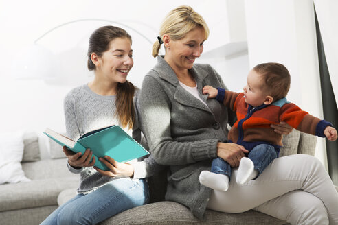 Mutter sitzt mit Tochter und kleinem Jungen auf der Couch und lächelt - GDF000593