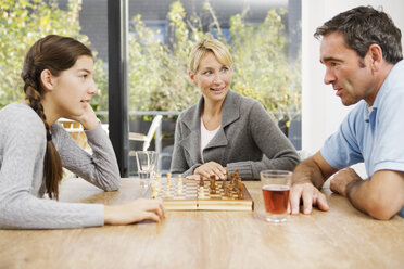 Vater und Tochter spielen zu Hause Schach, die Mutter schaut zu - GDF000602