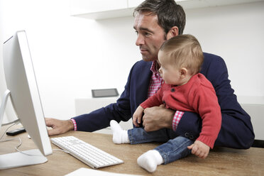 Businessman with baby boy working from home - GDF000610