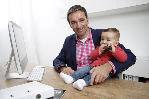 Businessman with baby boy working from home - GDF000615